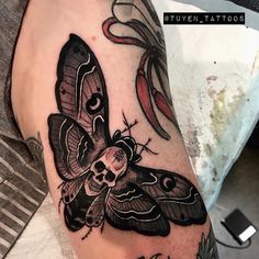 a black and grey moth tattoo on the arm