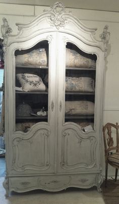 an old white armoire with pillows in it