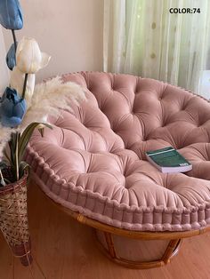 a pink round couch sitting on top of a wooden floor next to a vase filled with flowers