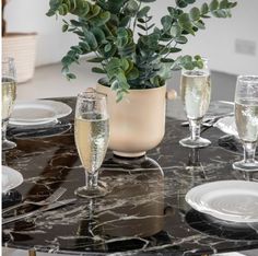 a table topped with wine glasses and a vase filled with greenery on top of it