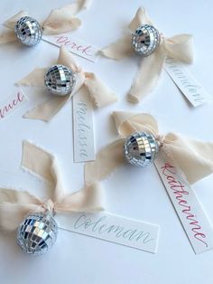 disco ball place card holders with ribbons and name tags on white table cloth, ready to be used as centerpieces