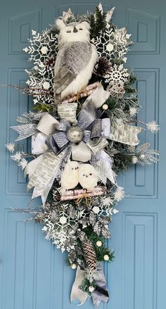 a wreath with an owl and snowflakes hanging on the side of a blue door