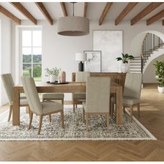 a dining room table with beige chairs and an area rug