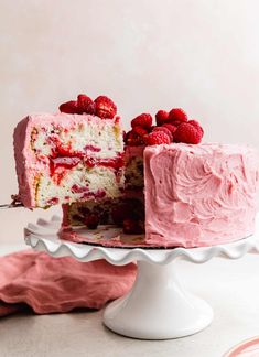 a close up of a cake with raspberry frosting and one slice missing