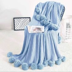 a blue blanket with pom poms on it sitting next to a white wall