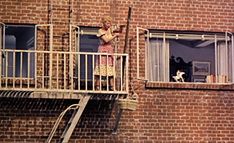 a woman standing on the balcony of a brick building