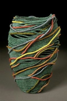 a green vase with multicolored yarn wrapped around it's sides on a black background