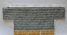 a piece of fabric with yellow and grey squares in it on top of a white surface