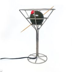 a black object with two sticks sticking out of it's sides and one red ball in the middle