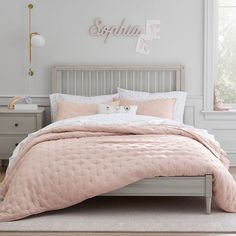 a white bed with pink comforter and pillows