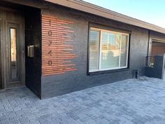 a black building with brick floors and two doors on each side of the building is an entry way that leads to another entrance