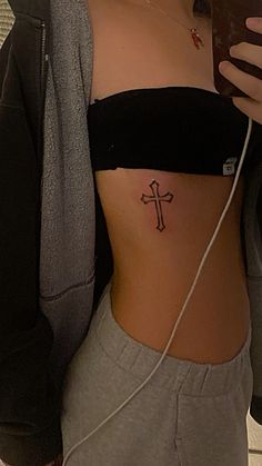 a woman with a cross tattoo on her stomach holding a cell phone and looking at the camera