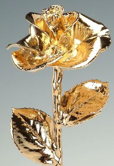 a gold colored metal rose with leaves on it