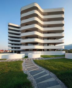 the building has many windows and balconies on it's sides, along with stone walkways