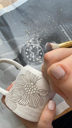 a person is holding a coffee cup and painting it