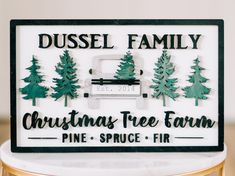 a christmas tree farm sign with pine trees and firs on the front, mounted on a marble pedestal