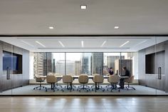 an empty conference room with two people sitting at a table in front of large windows