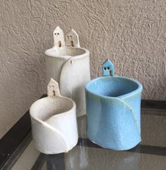 three vases sitting on top of a table next to each other, one blue and the other white