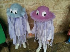 two children wearing hats with googly eyes and purple jellyfish tails, standing next to each other