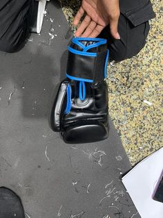 a pair of black and blue boxing gloves sitting on the ground next to someone's feet