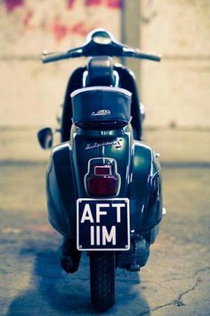 the back end of a motorcycle parked in front of a building with graffiti on it