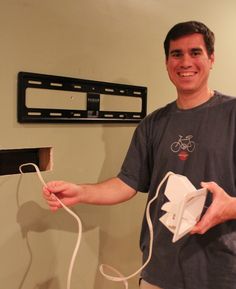 a man holding a wii remote and nunchuck in front of a wall mounted tv