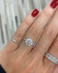 a woman's hand with three different rings on her fingers and one has a red manicure