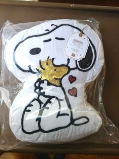 a snoopy dog pillow is wrapped in plastic and has gold sequins on it