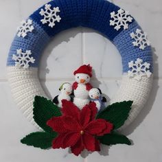 a knitted christmas wreath with snowflakes and poinsettis on it