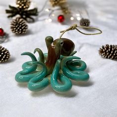 an octopus ornament on a table with pine cones