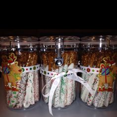 several glass jars filled with candy canes and pretzels in holiday themed wrappers