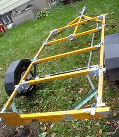 a yellow trailer with two wheels attached to it in the grass next to a house