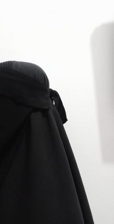 the back of a woman's black coat with a bow on her neck and hood