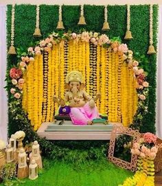 an idol sitting in front of flowers and greenery on the stage for a wedding ceremony