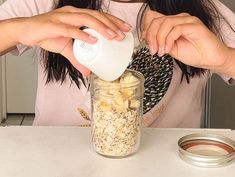 a woman is pouring oatmeal into a jar