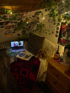 a laptop computer sitting on top of a bed next to a desk with a stuffed animal