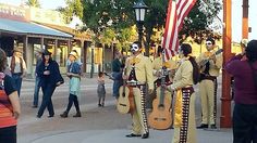 several people in costumes are walking down the street with guitars and an american flag on their head