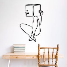 a drawing of a person reading a book on a wall above a desk with a chair