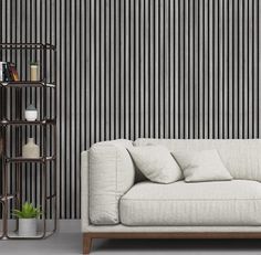 a white couch sitting in front of a wall with vertical stripes on it's side