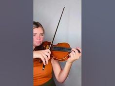 a woman in an orange shirt holding a violin