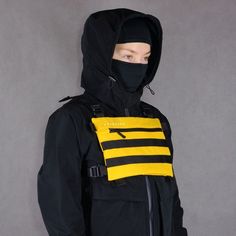 a man wearing a black and yellow jacket with a hood on it's face