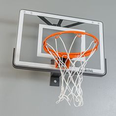 an orange basketball going through the hoop on a gray wall with a black and white net