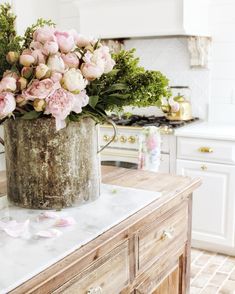 pink flowers are in an old watering can on a kitchen counter