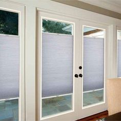 a living room filled with furniture and windows covered in cellular shades on the sliding glass doors