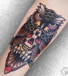 an owl tattoo on the arm with colorful colors and skulls around its neck, sitting on top of a woman's leg