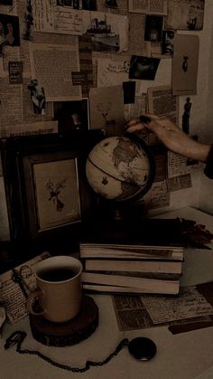 a table topped with books and a globe next to a cup of coffee on top of it