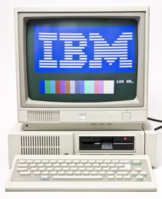 an old ibm computer with the ibm logo on it's screen and keyboard in front of it