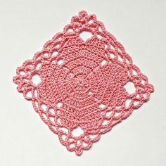 a pink crocheted doily on a white surface with the center piece cut out