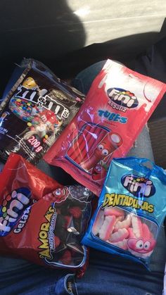 several bags of candy sitting in the back seat of a car, one is filled with gummy