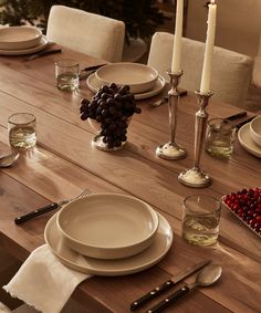 a wooden table topped with white plates and silverware